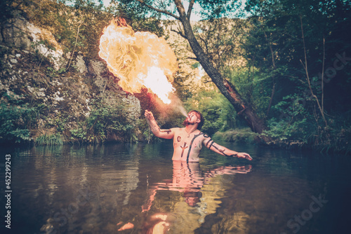 Man in a river blowing fire