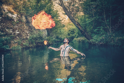 Man in a river blowing fire