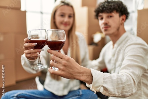 Young beautiful couple smiling happy toasting with red wine at new home