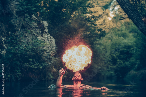 Man in a river blowing fire