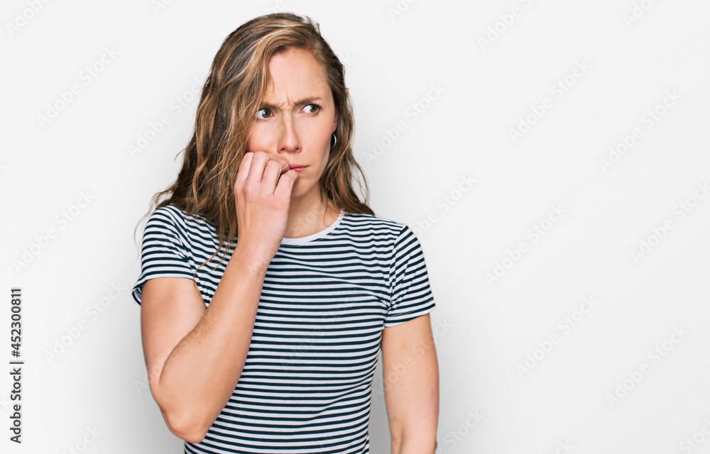 Young blonde woman wearing casual clothes looking stressed and nervous with hands on mouth biting nails. anxiety problem. Young blonde woman wearing casual clothes looking stressed and nervous with hands on mouth biting nails. anxiety problem.