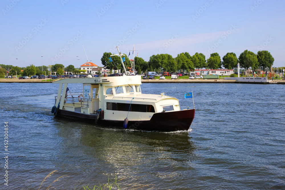 Roermond (Marina Resort Oolderhuuske), July 9. 2021: View on bicycle and passenger ferry over river Maas against blue summer sky