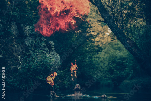 Man in a river blowing fire