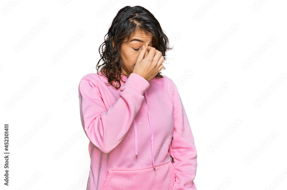 Young hispanic woman wearing casual sweatshirt tired rubbing nose and eyes feeling fatigue and headache. stress and frustration concept. Young hispanic woman wearing casual sweatshirt tired rubbing nose and eyes feeling fatigue and headache. stress and frustration concept.