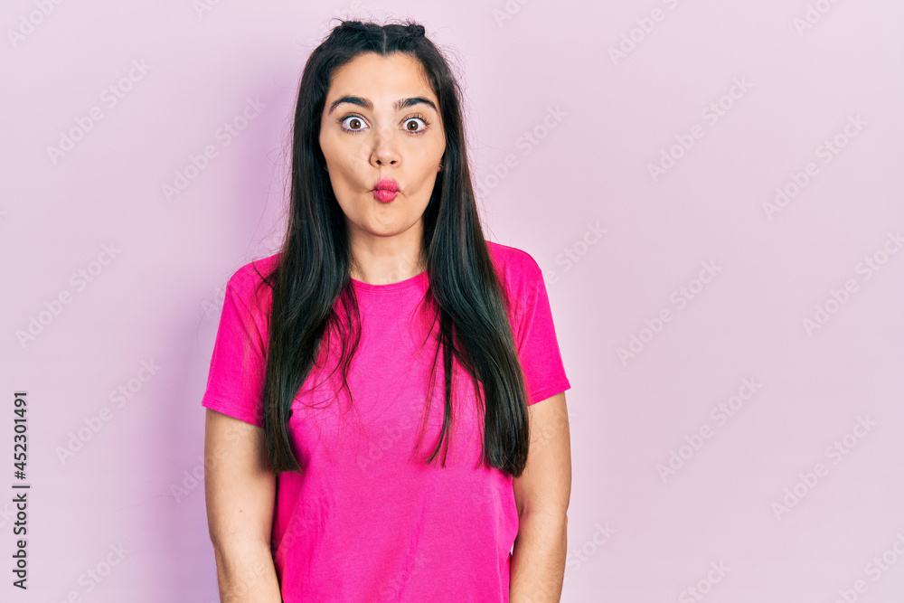 Young hispanic girl wearing casual pink t shirt making fish face with lips, crazy and comical gesture. funny expression. Young hispanic girl wearing casual pink t shirt making fish face with lips, crazy and comical gesture. funny expression.