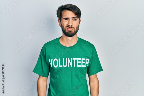 Young hispanic man wearing volunteer t shirt depressed and worry for distress, crying angry and afraid. sad expression.