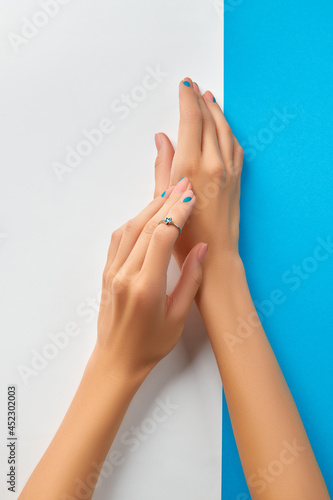 Womans hands with summer manicure on blue background. Manicure design trends