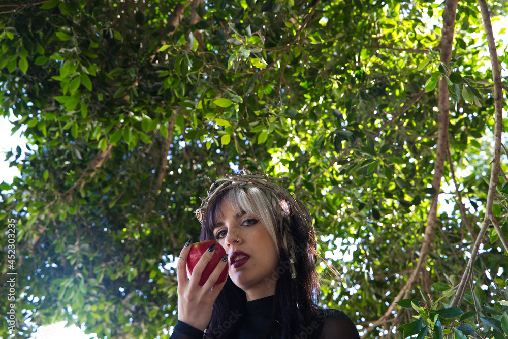 punky girl with blonde and brunette hair holding a red apple in her hands, the girl wears a crown of thorns like christ on her head. The girl is a witch from the fairy tale punky girl with blonde and brunette hair holding a red apple in her hands, the girl wears a crown of thorns like christ on her head. The girl is a witch from the fairy tale