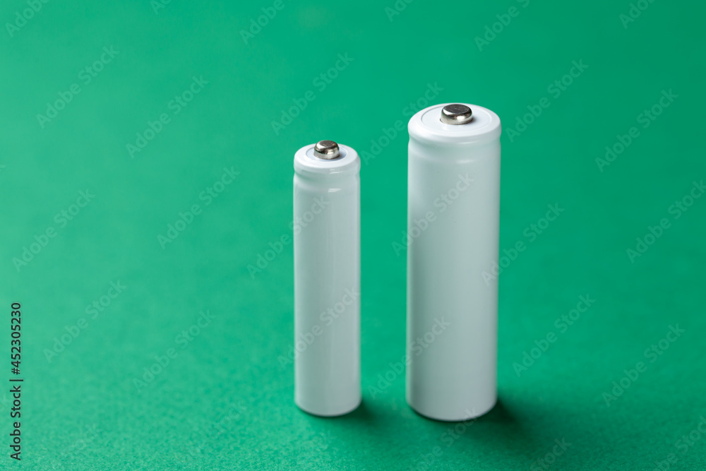 Several AA batteries in close up on a green background. Alkaline battery. Several AA batteries in close up on a green background. Alkaline battery.