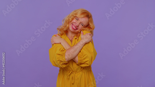Come to me, I want to embrace you. Redhead stylish girl in yellow dress spread hands and give hug to you. Pleasant expression, love feelings. Young woman on purple background. People sincere emotions