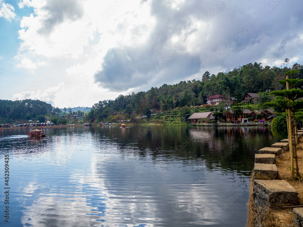 Fototapeta premium The beautiful lake and house reflection on the water at Ban Ruk Thai, which Yunnan Chinese Village at Mae Hong Son, Thailand.