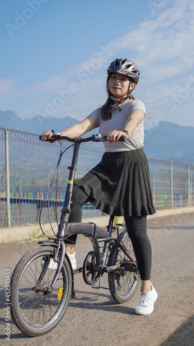young asian woman enjoying cycling when stopped in summer morning