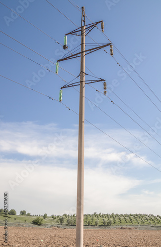 High-voltage concrete electric pole with wires on the background of the sky.