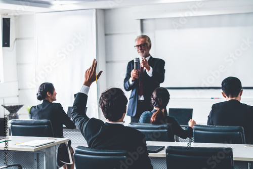 Senior leader speaker speaks to public people audience in training workshop or conference. Mature lecturer is CEO executive manager leading the symposium event. International business seminar concept.