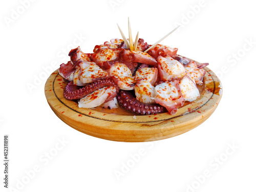 Pulpo a la gallega in Spanish meaning Galician-style octopus a traditional Galician dish served on the wooden plate isolated on white. photo