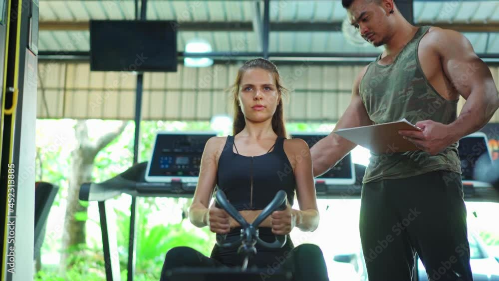 Asian Fitness trainer teach young sportswoman doing leg press exercise Asian Fitness trainer teach young sportswoman doing leg press exercise