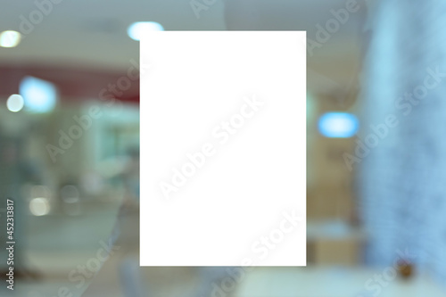 Mockup A4 white paper or white promotion poster displayed on the front of bright office interior, - stock photo