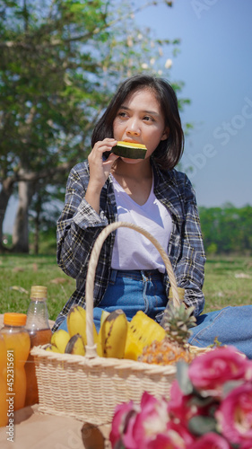 Young asian woman eating watermelon on vacation in park