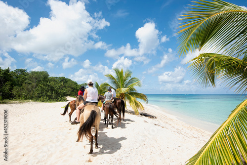 Rearview of a group of People on horseback at a tropical beach on the island of Cozumel in Mexico photo
