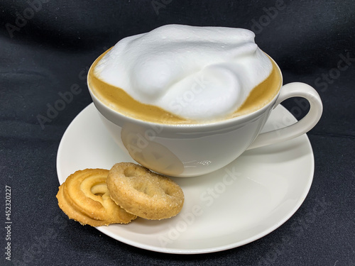 a cup of cappuccino coffee with Danish cookies in close-up