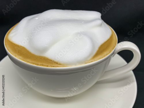 a cup of cappuccino coffee in close-up on a black background