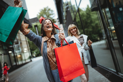 Beautiful happy women with shopping bags walking and having fun