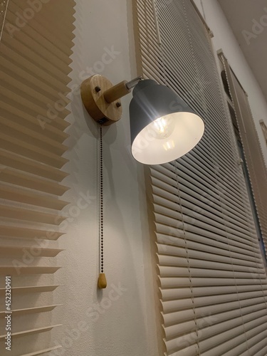 A lamp attached to the wall with a cover made of aluminum and yellow light looks calm and beautiful.