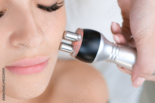 Young woman getting RF face lifting procedure in beauty salon.