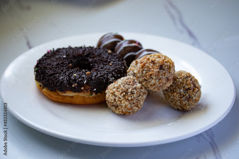 Chocolate coated donuts with glaze and nuts