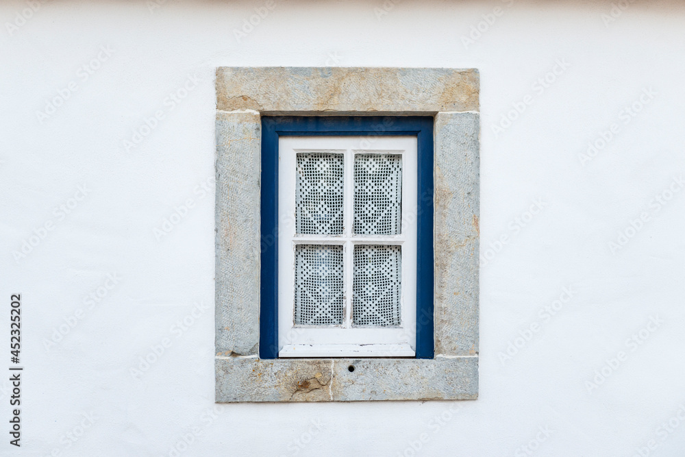 Detail of a traditional window on a white facade of a house, with crochet courtains, in Portugal. Detail of a traditional window on a white facade of a house, with crochet courtains, in Portugal.