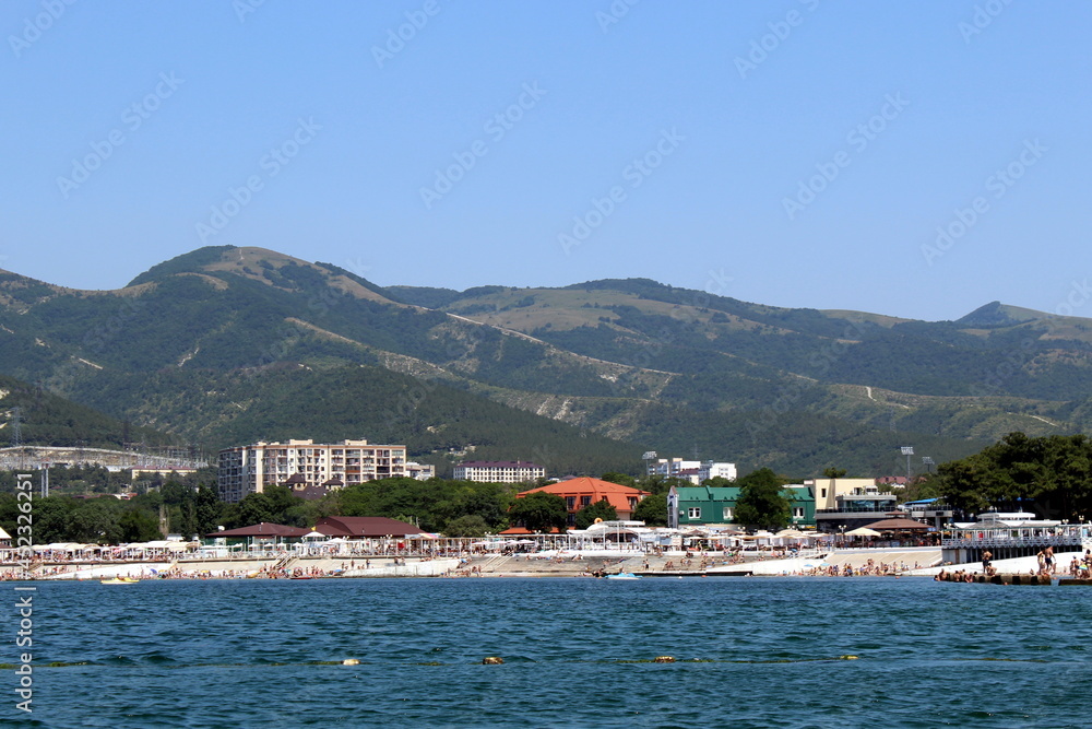Seascape. View from the sea. Summer beach with many people vacationing by the sea on a hot day.