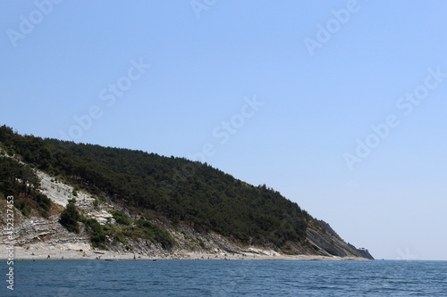 Seascape on the shore with tourists resting in hot sunny weather.