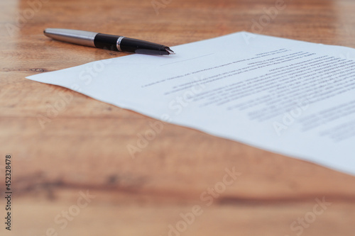 Pen and paper to sign on a wooden table. Concept of legality, contracts and documents photo