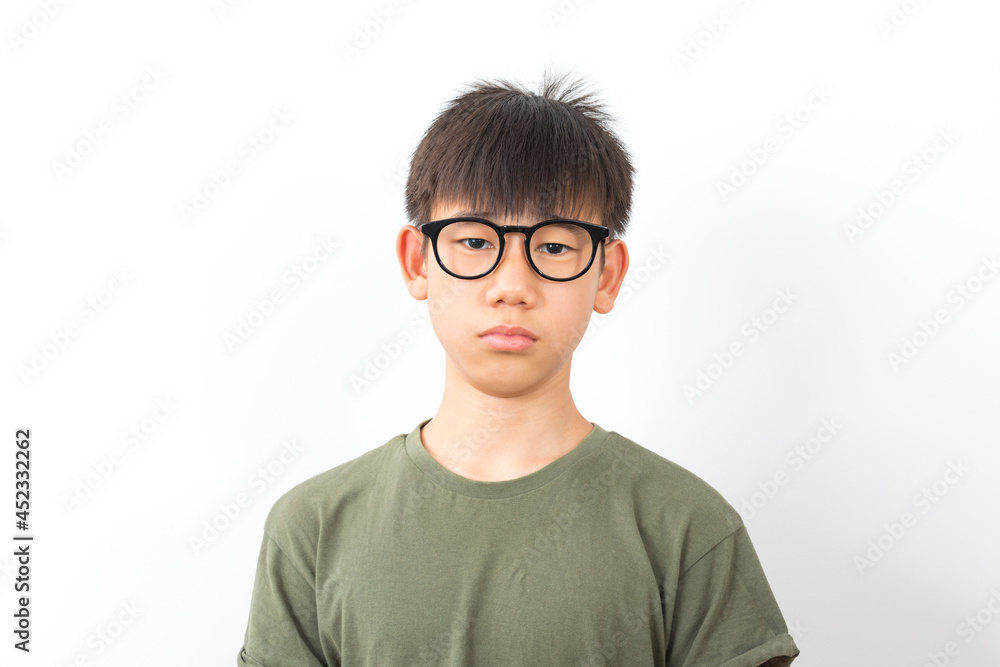 Frowning asian schoolboy wear glasses with serious look standing on white background.
