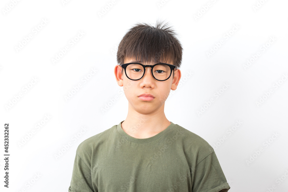 Frowning asian schoolboy wear glasses with serious look standing on white background. Frowning asian schoolboy wear glasses with serious look standing on white background.
