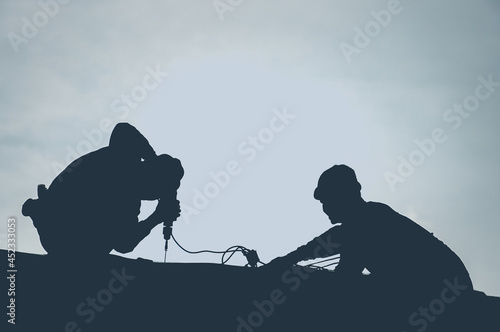 Silhouette workers on Roof with Sky in Background, install new roof, installing asphalt shingle, Construction concepts
