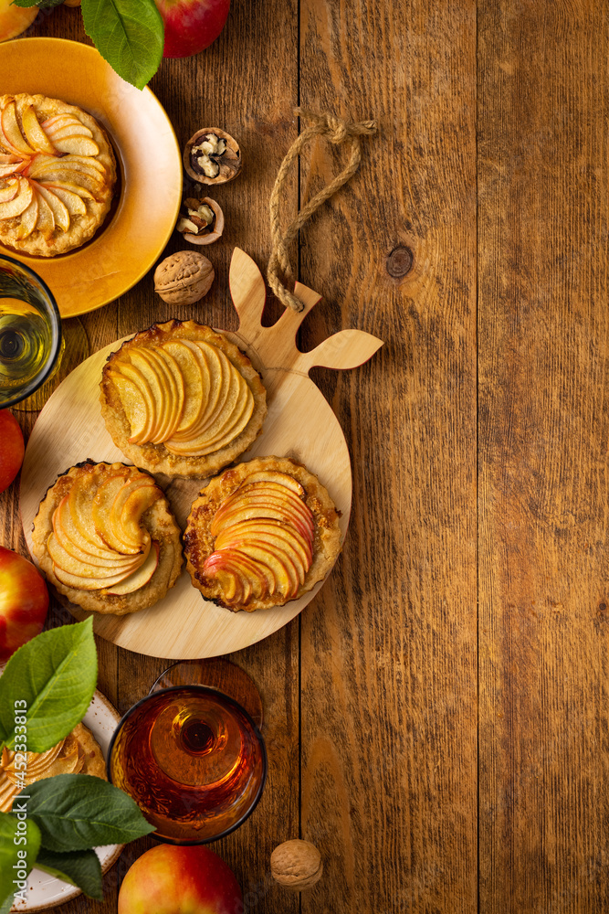 Mini Apple pie tartlets with walnut on wooden table. Delicious dessert for autumn winter dinner.Top view. Mini Apple pie tartlets with walnut on wooden table. Delicious dessert for autumn winter dinner.Top view.