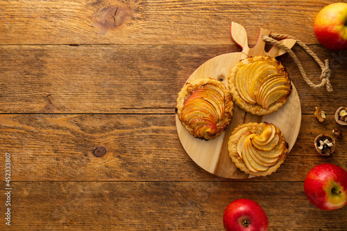 Mini Apple pie tartlets with walnut on wooden table. Delicious dessert for autumn winter dinner.Top view.