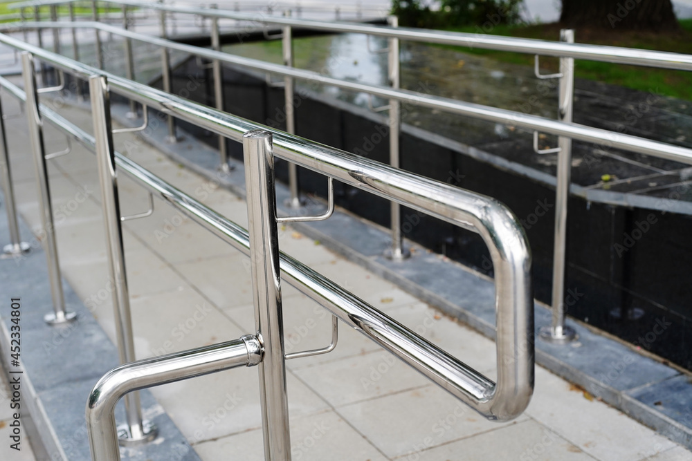 Stainless steel railings installed on a public ramp. Close-up. Selective focus