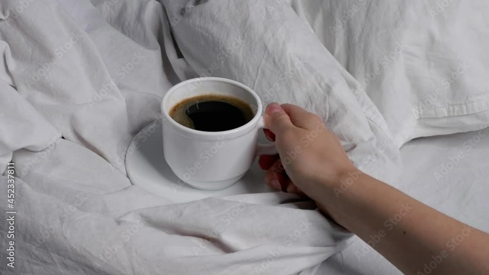 The girl drinks black coffee in bed. Breakfast in bed. Cosiness. Interior.