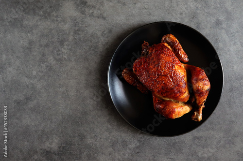 Grilled chicken with a delicious fried crust on a black plate. Chicken cooked on the fire. Barbecue chicken. Bbq. Baked bird.