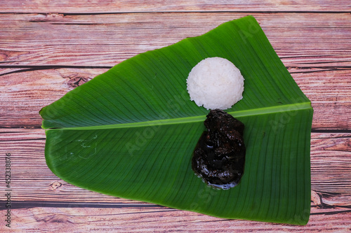 Cooked rice and  chicken cooked in soy sauce or Ayam Masak Kicap  on banana leaf photo