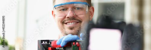 Blogger demonstrates on camera repair of computer board photo