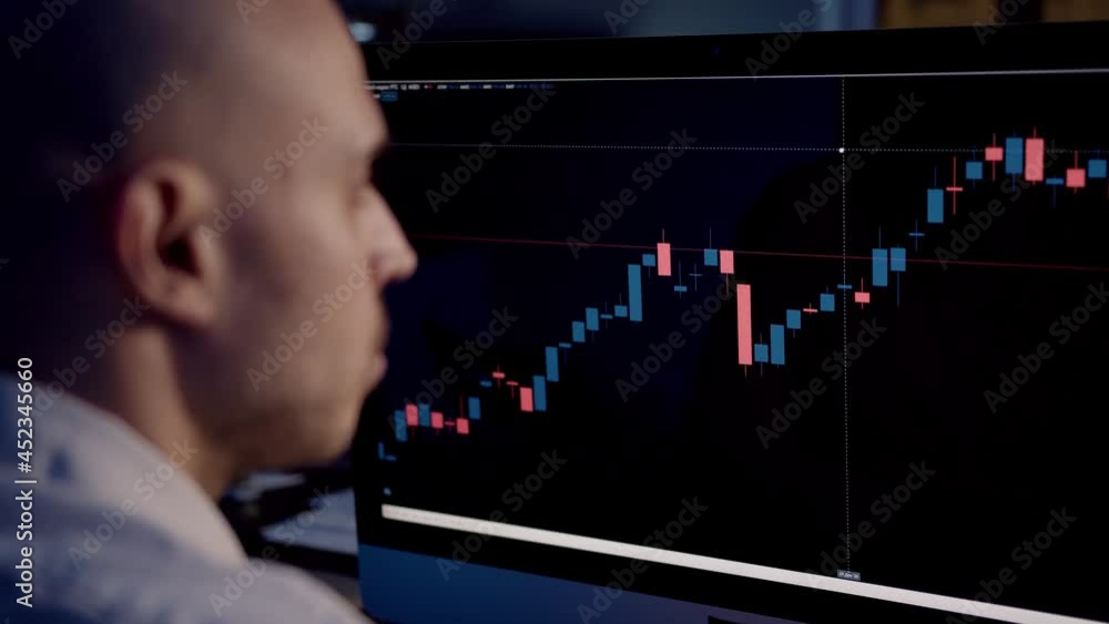 Stock trader with bar charts rise and fall, stock market on computer screen. Blurred man with bald head carefully studying the screen with stock graphs, gimbal shot Stock trader with bar charts rise and fall, stock market on computer screen. Blurred man with bald head carefully studying the screen with stock graphs, gimbal shot