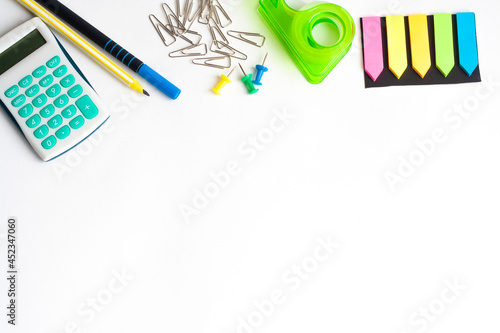 Calculator, pen, pencil, paper clips, tape and paper bookmarks on a white background, copy space