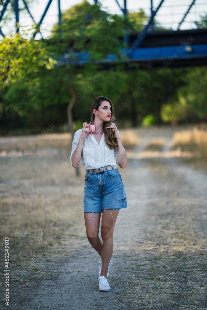 Chica joven al atardecer en un parque natural con smartphone y cascos Chica joven al atardecer en un parque natural con smartphone y cascos