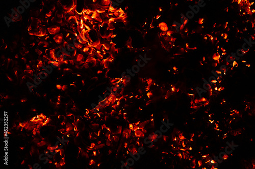 background of burning and glowing hot coals. smoldering embers of fire. flicker of burning coals at night