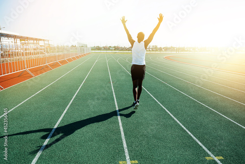 Fotografi A black male track and field athlete in a white mauka runs along the track at th