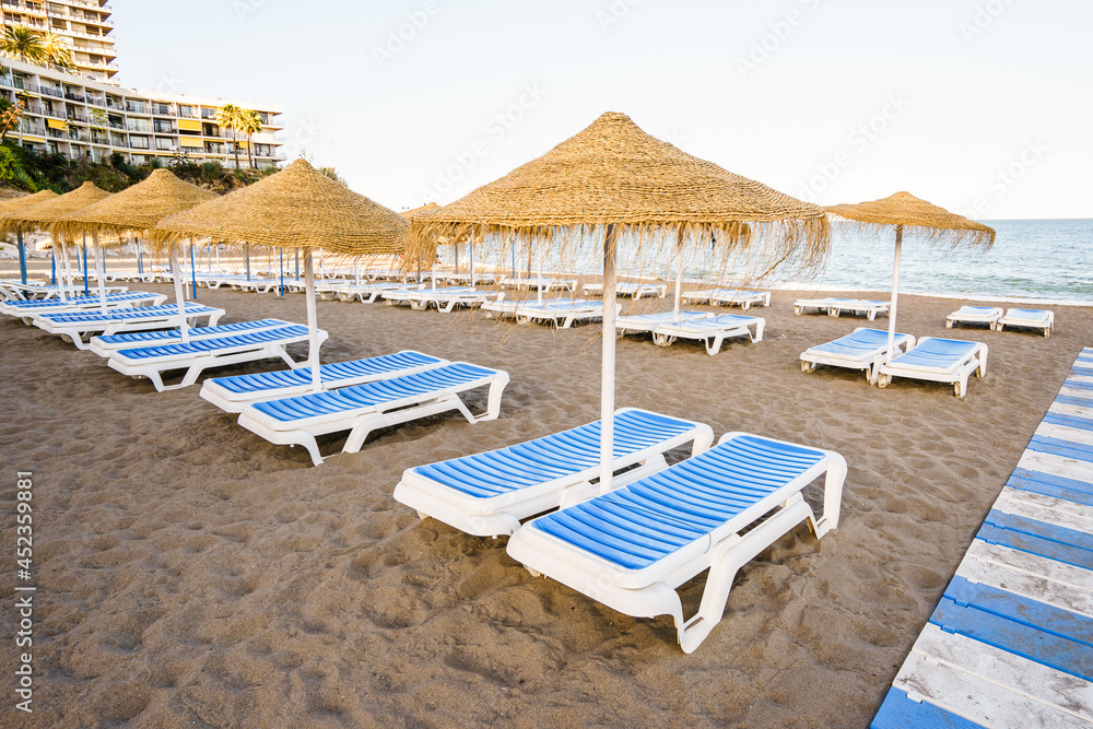 Beautiful beach with deckchairs and umbrellas against of blue sky