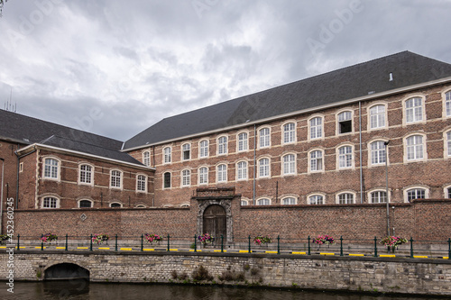 Gent, Flanders, Belgium - July 30, 2021: Brown brick building and wall along Lieve River is monastery of Augustinian monks under rainy gray cloudscape. photo